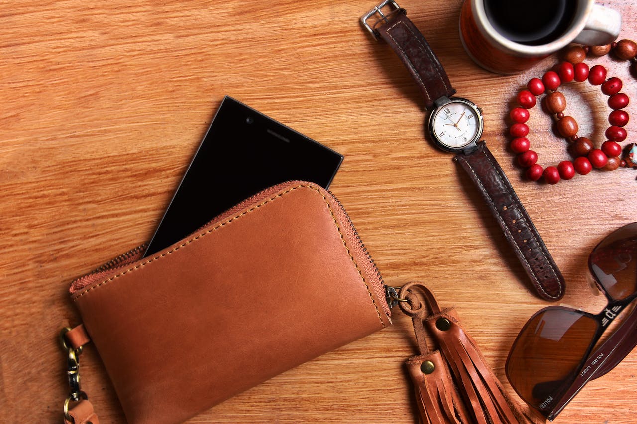 menu-01 Flat lay of leather wallet, wristwatch, sunglasses, and coffee on wooden surface.
