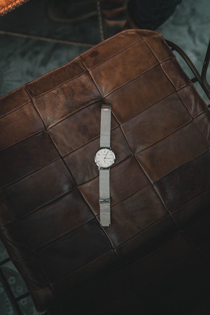 about-03 Elegant silver wristwatch resting on a brown leather seat, showcasing elegance and style.
