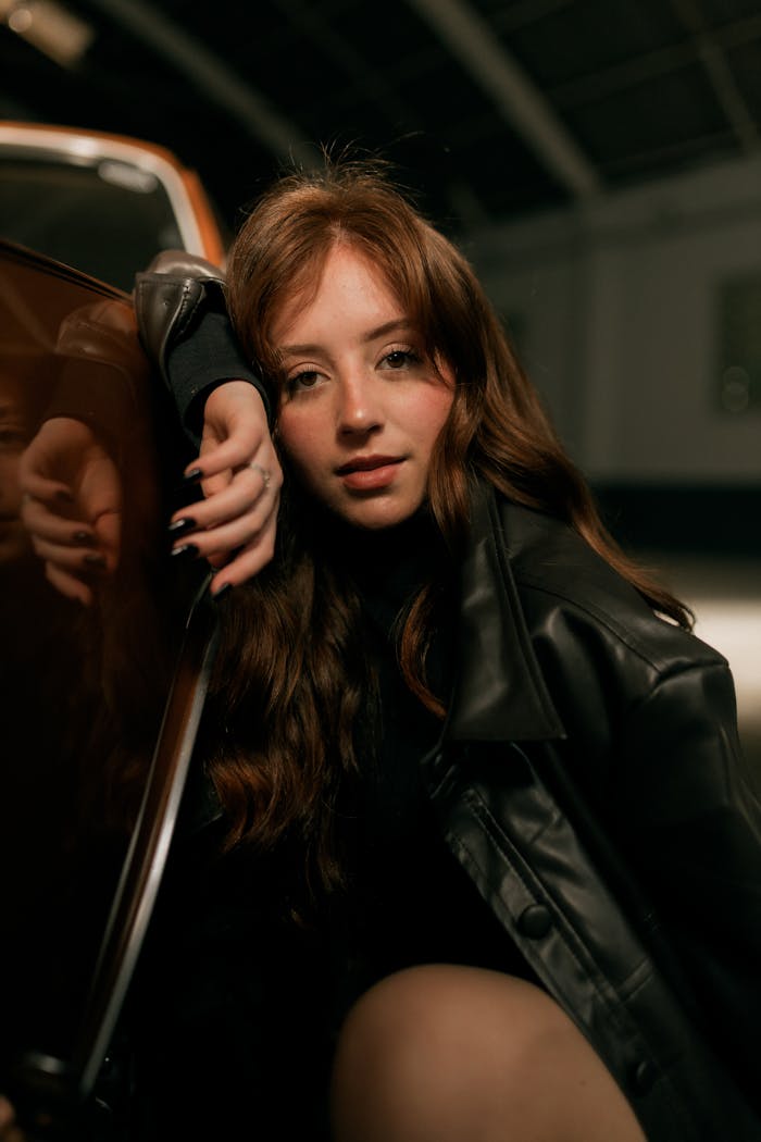 about-01 Close-up portrait of a young woman in a leather jacket indoors.
